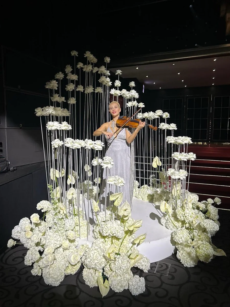 Violinist performing surrounded by hanging flowers at Megan and Karan’s wedding