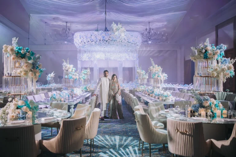 Shifa and Shahzeb surrounded by flowers and chandeliers at their Dubai wedding