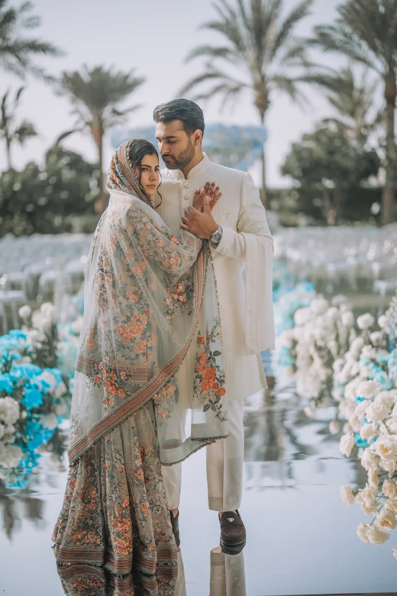 Shifa and Shahzeb beside their outdoor floral wedding arch