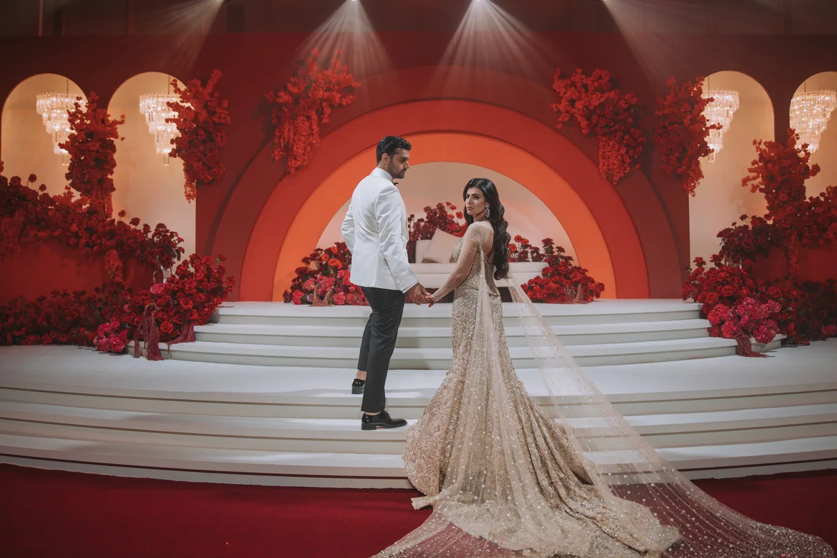 Shifa and Shahzeb beneath a red floral wedding backdrop