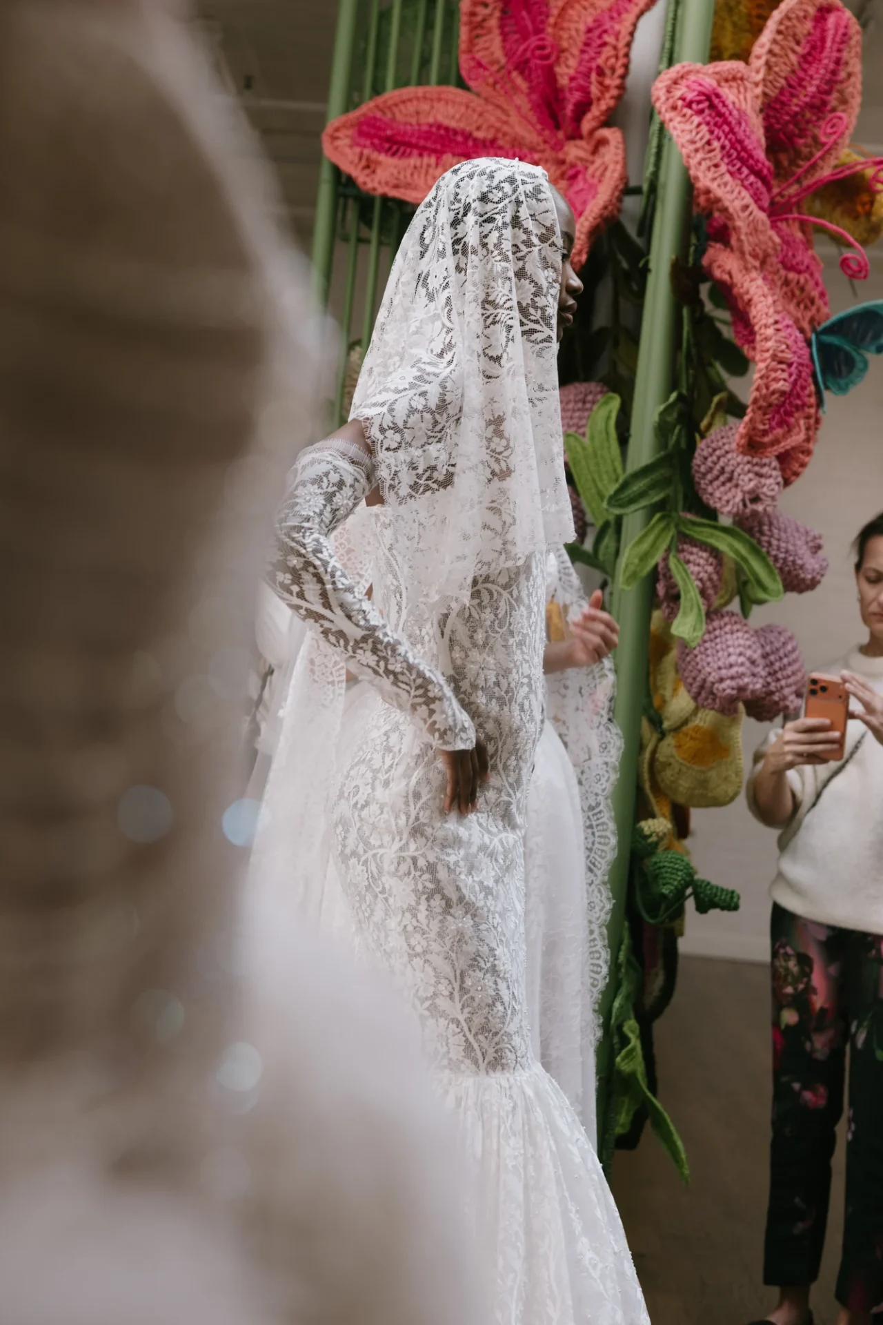 A lace cape and embroidered gown framed by the handwoven garden installation