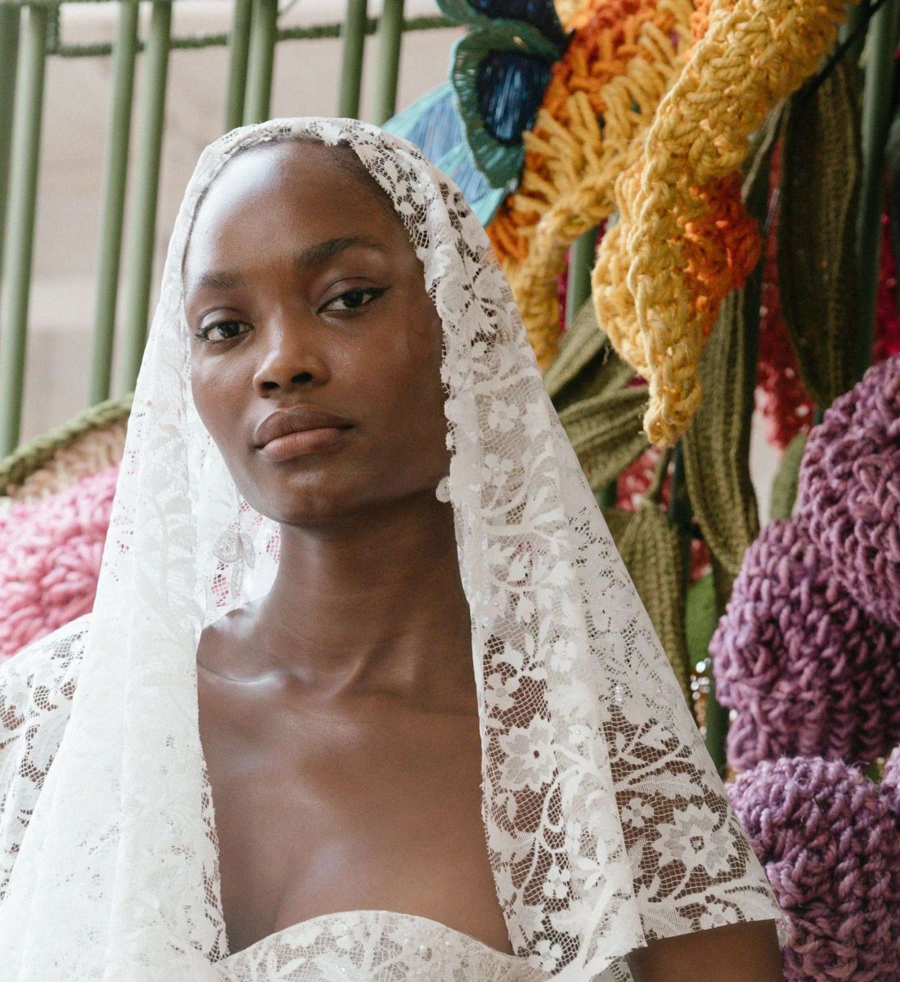 A dark-skinned model wearing the soft bridal makeup, framed from head to bust