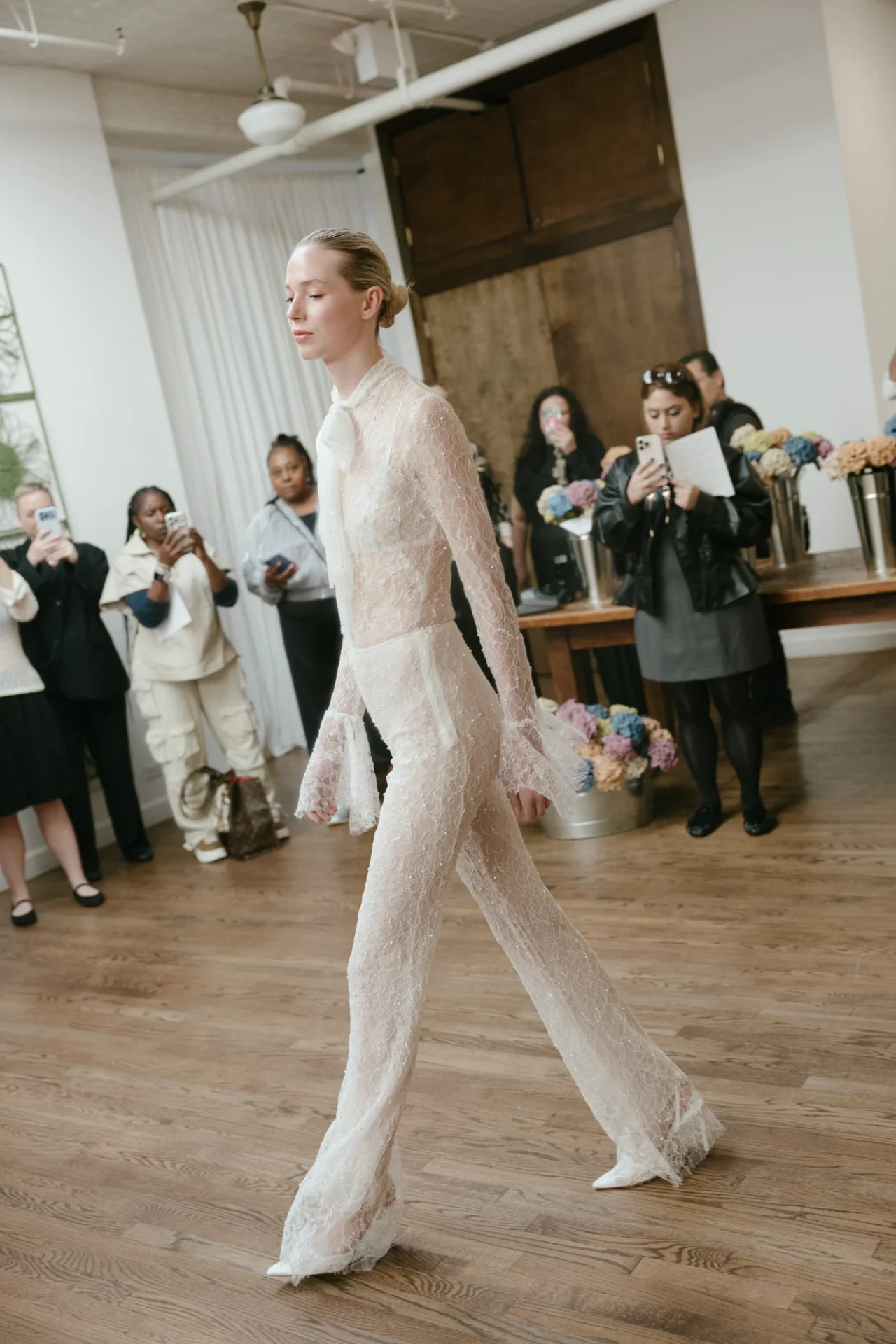 A model in a lace look walks through the Chelsea presentation as guests watch