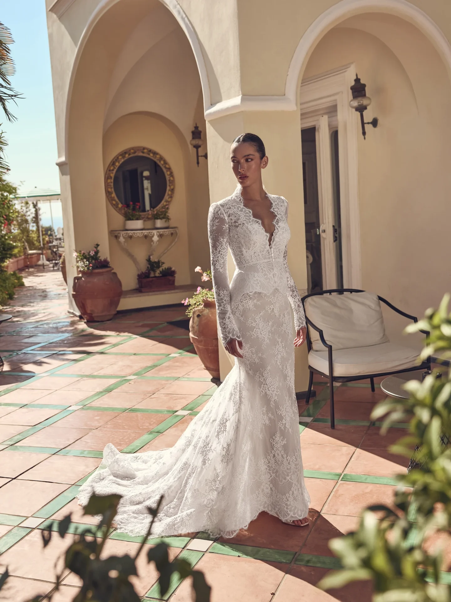 Ricca Sposa Couture Capri 2028 style 28-012, with long lace sleeves, a fitted skirt, and a peplum at the waist.